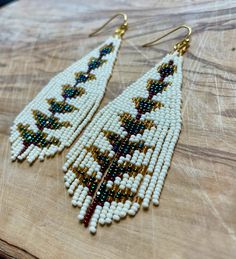 two pairs of beaded earrings sitting on top of a wooden table