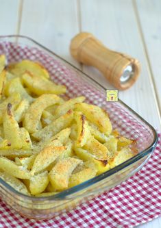 a glass casserole dish filled with cheesy potatoes on a red and white checkered cloth