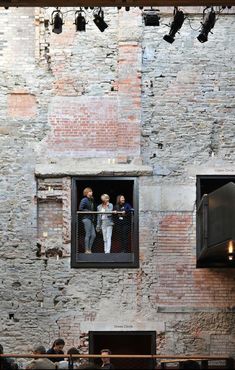 people are standing in the window of an old brick building