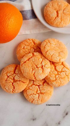 several orange cookies on a white plate next to an orange