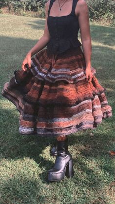 a woman standing in the grass wearing a dress