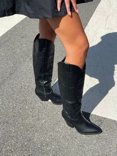 The Abigail Boot is a sleek knee-high cowboy boot with an angular look. A snipped toe and a block heel set on a slant complement the subtle western decorative stitching and panel cuts. Pair with a cute dress or wear over leggings for an all season, on trend look! Fit true to size. 3" heel. We recommend sizing down 1/2 size. Length:20"Width:3.5" Tall Black Cowboy Boots Outfit, Tall Black Cowboy Boots, Shoe Poses, Thrifting Manifestation, Cowboy Boots Street Style, Black Cowboy Boots Outfit, Knee High Western Boots, Knee High Cowboy Boots, Black Cowgirl Boots