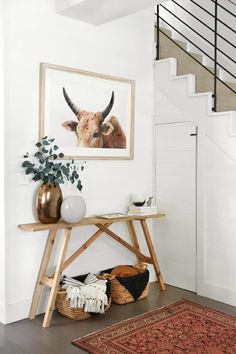 a room with a rug, vases and pictures on the wall next to stairs