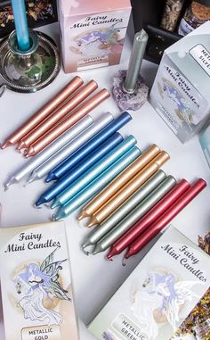 many different colored pens are on a table next to some boxes and candle holders with candles in them