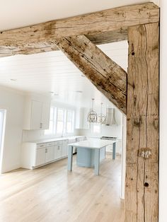 an open kitchen and dining room area with wood beams in the ceiling, white walls and flooring