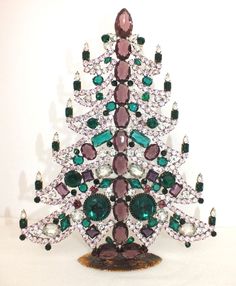 a christmas tree made out of jewels on a white surface with green and purple stones