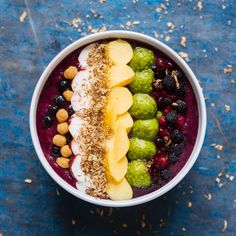 a bowl filled with fruit and nuts on top of a blue surface