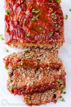 sliced meatloaf with sauce and parsley on top, ready to be eaten