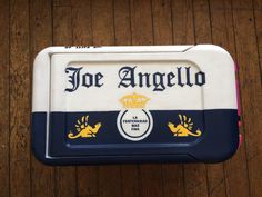 an ice box with the name joe angello on it sitting on a wooden table