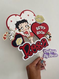 a hand holding a sticker that says betty boop and has hearts on it