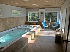 an indoor jacuzzi tub with chairs and windows