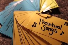 several yellow and blue tags with the words preschool songs written on them