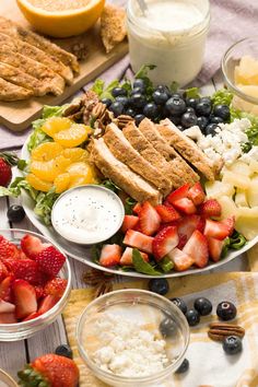 an assortment of fruits and vegetables on a table with dips, yogurt, strawberries