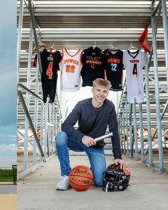 a man kneeling down next to a basketball and jersey rack with shirts hanging on it