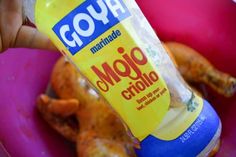 a hand holding a bottle of mayonnaise in a pink bowl with chicken wings