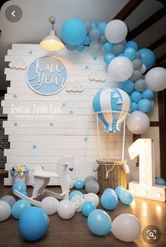 balloons and streamers are on the floor in front of a backdrop for a baby's first birthday