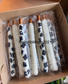 four toothbrushes wrapped in plastic and decorated with black flowers are sitting in a cardboard box