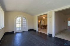 an empty living room with large windows and tile flooring in front of the door