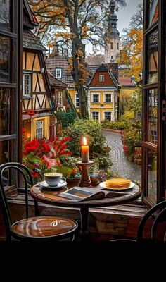 an open window with a table and chairs in front of it, looking out onto the street