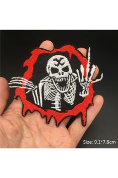 a hand holding a patch with a skeleton on it