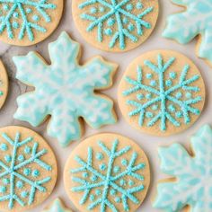 decorated cookies with blue frosting and snowflakes on them are arranged in rows