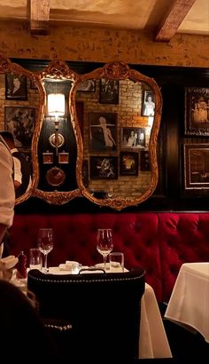 a man sitting at a table in front of a mirror with pictures on the wall