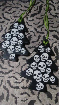 two christmas trees decorated with skulls and green ribbons on a black and white tablecloth