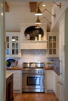 a kitchen with white cabinets and stainless steel stove top oven in the middle of the room