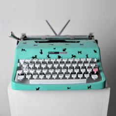 an old fashioned typewriter sitting on top of a white pedestal next to a wall