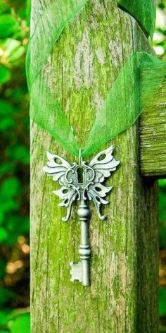 an old key is attached to a wooden post with a green ribbon around it and some trees in the background