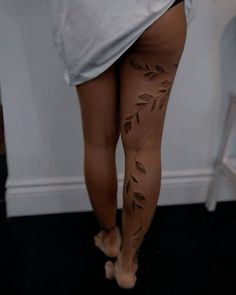 a woman's leg with leaves on it and no shoes in the room behind her