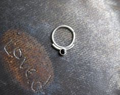 This simple septum ring is handcrafted in sterling silver and set with a 2.5mm black spinel.  Available in 7,8,9 mm diameters Minimalist Silver Jewelry With Black Spinel, Minimalist Silver Black Spinel Jewelry, Minimalist Internally Threaded Sterling Silver Septum Ring, Minimalist Hand Forged Black Rings, Black Septum Ring Gift, Tooth Ring, Whale Necklace, Brass Hoop Earrings, Brass Hoops