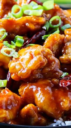 chicken with sauce and green onions in a black bowl