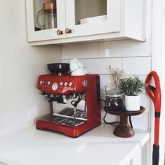 a red espresso machine sitting on top of a white counter