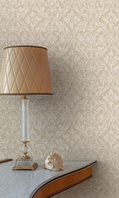 a lamp sitting on top of a wooden table next to a wallpapered wall