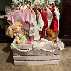 a wooden crate filled with baby clothes and a doll