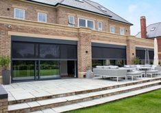 an outdoor patio with steps leading up to the back door and covered in black roller shades