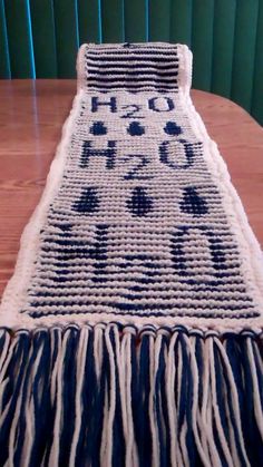 a close up of a knitted table runner on top of a wooden table with blue and white stripes