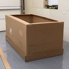 a cardboard box sitting on top of a floor next to a wall and some boxes