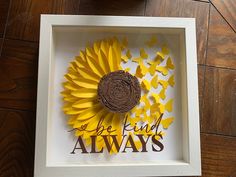 a paper sunflower with the words be kind of always on it in a shadow box