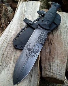 a knife with a skull on it sitting on top of a piece of wood