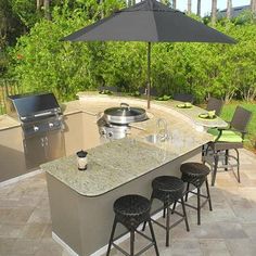 an outdoor kitchen with bar stools and an umbrella over the grill area is shown