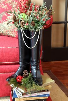 a pair of black boots sitting on top of a pile of books next to a christmas tree