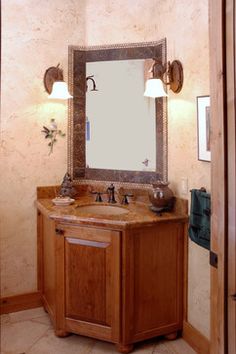 a bathroom with a sink, mirror and lights on the side of the door way