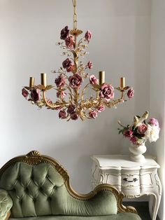 a chandelier hanging from the ceiling over a couch in a room with white walls