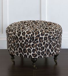 a leopard print ottoman sitting on top of a hard wood floor next to a white wall