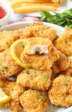 some fried food on a white plate with lemon wedges and parmesan cheese