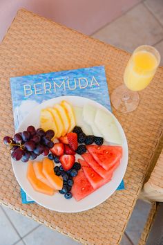 a white plate topped with fruit next to a glass of orange juice