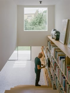 a man standing in front of a book shelf filled with books