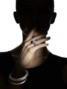 a woman in black shirt holding her hand up to her face with two rings around her neck